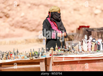 Femme musulmane en costume traditionnel, entièrement couvert, de la vente ses produits sur un stand à Petra, en Jordanie. Banque D'Images