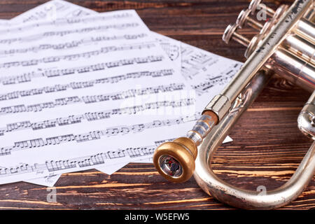 Vieilles trompettes et notes de musique sur fond de bois. Banque D'Images