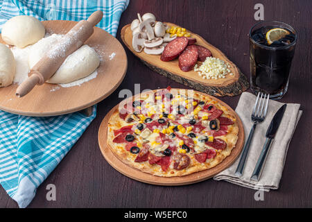 Menu restaurant Pizza Pizza épicée - délicieux avec les saucisses et les champignons. La pizza sur la table en bois rustique avec des ingrédients. Banque D'Images