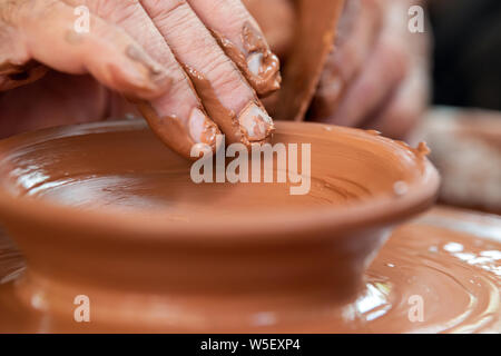 Les mains de potter. Le potter qui fait des plats de poterie sur tour de potier. Le sculpteur à l'atelier d'argile rend libre Banque D'Images