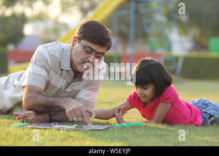 Fille jouant jeu de mot dans un parc avec son grand-père Banque D'Images