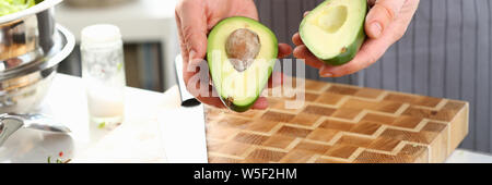 Male Hands Holding les moitiés de fruits Avocat vert Banque D'Images