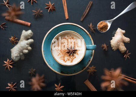 Tasse à thé indien Masala lévitation avec épices et la cannelle sur le tableau noir. Vue d'en haut. Banque D'Images