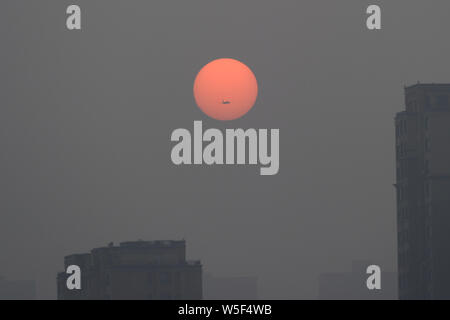 Le soleil et les immeubles de grande hauteur sont vu vaguement dans le smog lourde à Dalian city, Liaoning Province du nord-est de la Chine, le 4 mars 2019. Banque D'Images