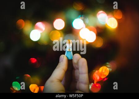 Figurine miniature en plastique d'une jeune fille de neige sur le flou Arrière-plan de l'arbre de Noël Banque D'Images