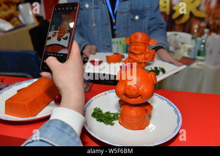 Un visiteur prend des photos d'un assaisonnement piquant plat-réchaud avec forme de cochon au cours de la 100e foire de la nourriture et des boissons de la Chine dans la ville de Chengdu, southwe Banque D'Images