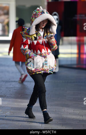 Un jeune Chinois femme marche dans la rue Sanlitun, Beijing, Chine, 21 mars 2019. Un front froid souffle sur la plupart des régions de Ch Banque D'Images