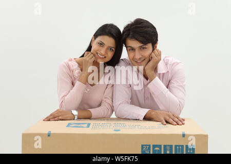 Couple indien penché au-dessus d'une boîte en carton et souriant Banque D'Images