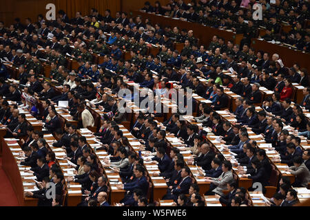 Adjoints suivent la troisième séance plénière de la deuxième session de la 13e Assemblée populaire nationale (APN) dans le Grand Hall du Peuple de Pékin en Banque D'Images