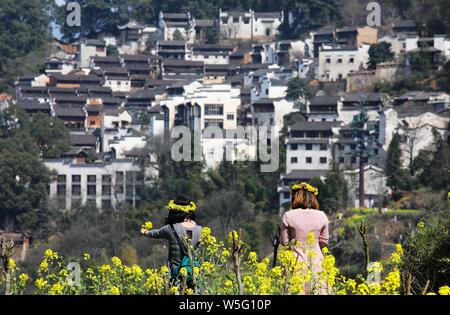 Des touristes posent pour des photos avec les fleurs de colza en pleine floraison dans l'ancien village de Huangling comté de Wuyuan Shangrao, ville, à l'est Chi Banque D'Images