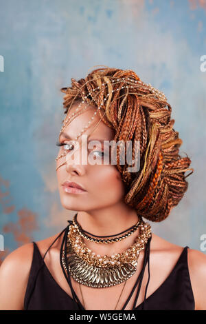 Saveur du sud. Portrait d'une femme bronzée luxueux, pensive, élégant, avec une coiffure exotique et grand bijoux, collier, boucles d'oreille. Banque D'Images