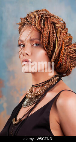 Saveur du sud. Portrait d'une femme bronzée luxueux, pensive, élégant, avec une coiffure exotique et grand bijoux, collier, boucles d'oreille. Banque D'Images