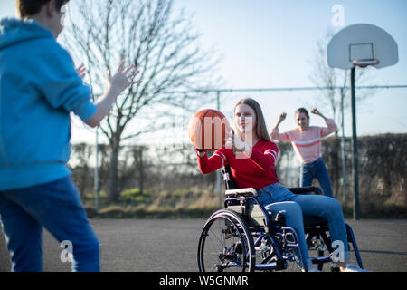 Adolescente en jouant au basket-ball en fauteuil roulant avec des amis Banque D'Images