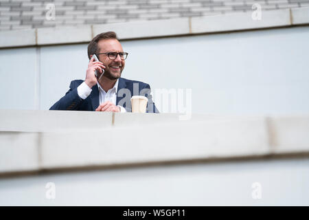 Mature Businessman Prendre appel sur téléphone mobile à l'extérieur permanent Office Building Banque D'Images