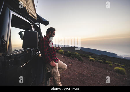 Utiliser l'homme voyageur Aventure explorer téléphone portable avec connexion internet en montagne sauvage place lors des voyages d'excursion avec off road voiture noire et Banque D'Images