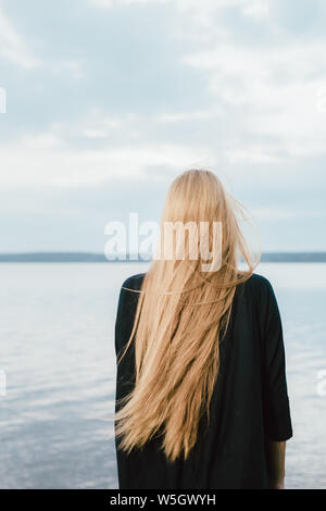 Long haired woman looking at Lake le jour d'été Banque D'Images