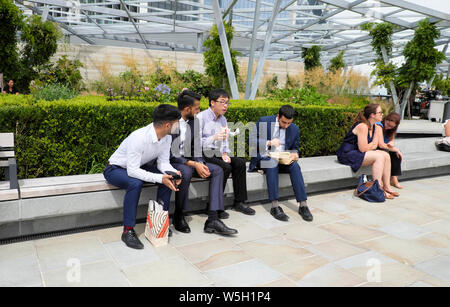 Les gens à l'heure du déjeuner assis sur des bancs mangeant le déjeuner sur la terrasse sur le toit au jardin au 120 Fenchurch Street dans la ville de Londres Royaume-Uni KATHY DEWITT Banque D'Images