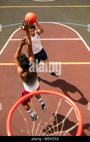 L'un des jeunes joueurs de basket-ball interculturel attaquant la balle de rival Banque D'Images