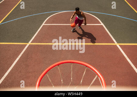 Jeune joueur professionnel de basket-ball avec ballon sur cour Banque D'Images