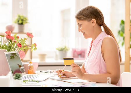 Jolie fille avec une carte en plastique va acheter quelque chose dans la boutique en ligne Banque D'Images