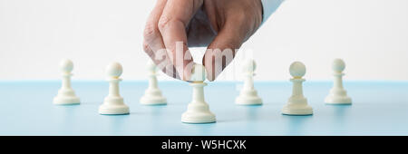 Voir l'échelle de l'image de l'homme main tenant la première de nombreuses pièces des échecs pion placé sur bleu 24 dans une image conceptuelle. Banque D'Images