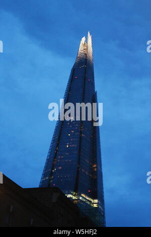 Shard à Londres, au Royaume-Uni dans une couleur bleuâtre et lumières dans les fenêtres tourné en un faible angle de vue. La photo a été prise la nuit et un jour nuageux. Banque D'Images