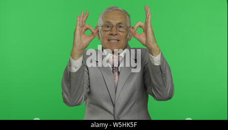 Personnes âgées businessman showing ok geste. Vieil homme en donnant l'usure formelle bon signe sur l'incrustation couleur arrière-plan. Symbole de l'accord et la réussite. Arrière-plan de l'écran vert Banque D'Images