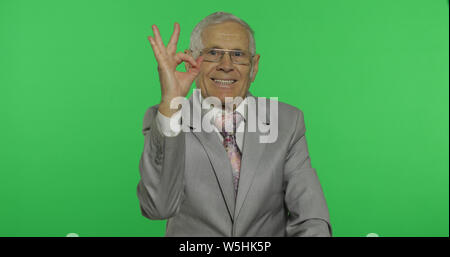 Personnes âgées businessman showing ok geste. Vieil homme en donnant l'usure formelle bon signe sur l'incrustation couleur arrière-plan. Symbole de l'accord et la réussite. Arrière-plan de l'écran vert Banque D'Images