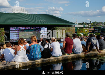 Fans et spectateurs sur Henman Hill , Murray Mound ou Aorangi Hill avec le grand écran sur la Cour n° 1 durant les championnats de Wimbledon 2019. Banque D'Images