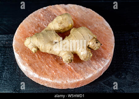 Les racines de gingembre frais sel rose de Perse sur board close up sur fond de bois noir, concept alimentaire asiatique Banque D'Images