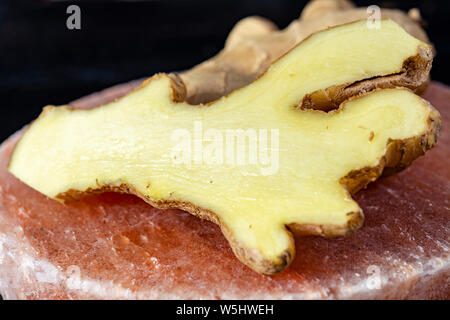 Les racines de gingembre frais sel rose de Perse sur board close up sur fond de bois noir, concept alimentaire asiatique Banque D'Images