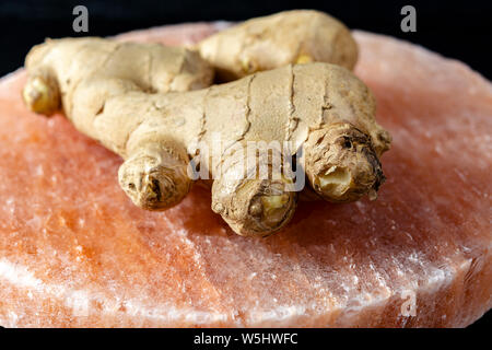 Les racines de gingembre frais sel rose de Perse sur board close up sur fond de bois noir, concept alimentaire asiatique Banque D'Images