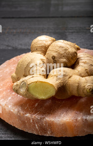 Les racines de gingembre frais sel rose de Perse sur board close up sur fond de bois noir, concept alimentaire asiatique Banque D'Images