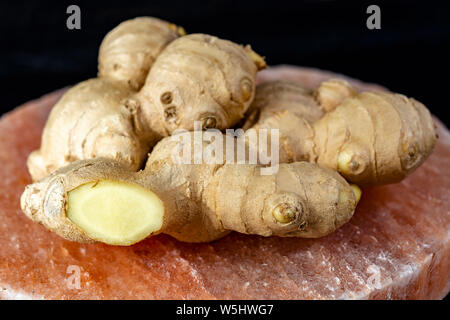 Les racines de gingembre frais sel rose de Perse sur board close up sur fond de bois noir, concept alimentaire asiatique Banque D'Images