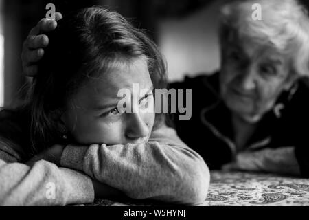 Vieille dame mamie réconfortant d'une petite fille pleurer sa petite-fille. Photo en noir et blanc. Banque D'Images