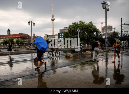 29 juillet 2019, Berlin : les passants tentent de se protéger avec des parasols. Photo : Britta Pedersen/dpa-Zentralbild/dpa Banque D'Images