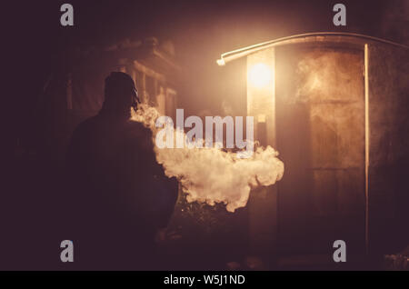 Homme étrange fumeurs dans la nuit avec un grand effet de la vapeur de la cigarette Banque D'Images