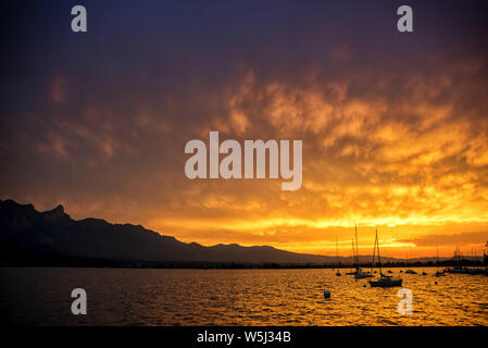 Nuages soleil après le coucher du soleil comme dans un four en plein souffle avec Stockhorn de montagnes, le lac de Thoune et sur les bouées d'ancrage des bateaux à voile Banque D'Images