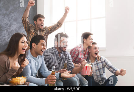 Groupe de jeunes amis regarder du sport à la télévision et acclamer Banque D'Images