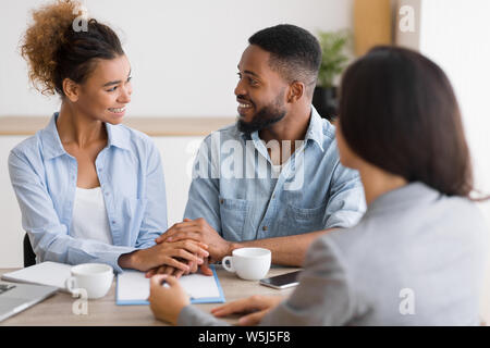 Smiling african american couple holding hands in Bureau du conseiller financier Banque D'Images