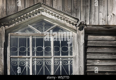 Un fragment de la fenêtre de l'ancienne église en bois orthodoxe avec barres en fer forgé et chambranles en bois sculpté Banque D'Images