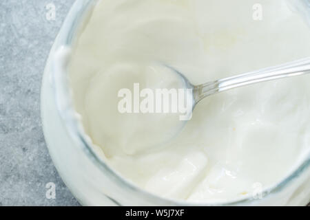 Yaourt de chèvre faits maison dans un bol en verre avec cuillère / crème probiotiques. Produit biologique. Banque D'Images