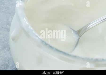 Yaourt de chèvre faits maison dans un bol en verre avec cuillère / crème probiotiques. Produit biologique. Banque D'Images