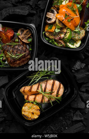 Close up de poissons grillés, de viande et de légumes dans des boîtes à emporter Banque D'Images