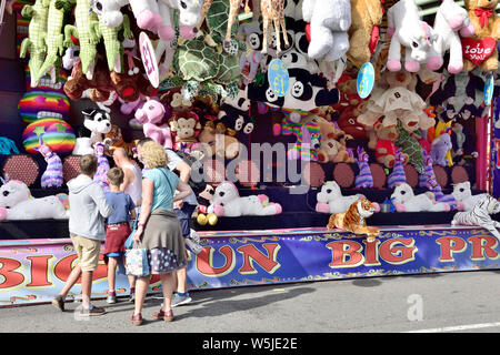 Famille avec enfants à la fête foraine stall à lancer des fléchettes à bord pour gagner jouets câlins. Le port de Bristol, UK Festival Banque D'Images