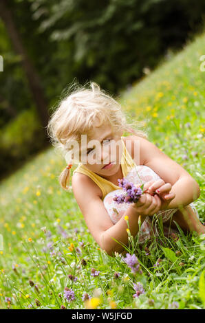 Belle fille blonde sitting on meadow Banque D'Images