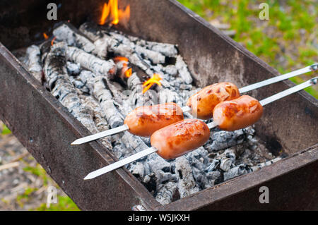 Griller les saucisses sur la grille du barbecue. Barbecue dans le jardin. Banque D'Images