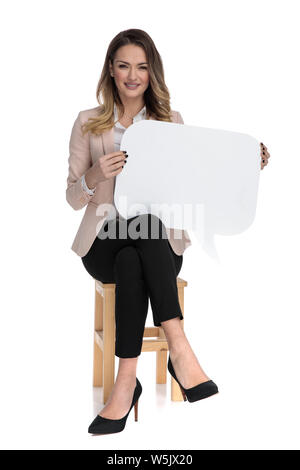 Businesswoman sitting cross-legged détient bulle et sourit tout en restant assis sur chaise en bois sur fond blanc Banque D'Images