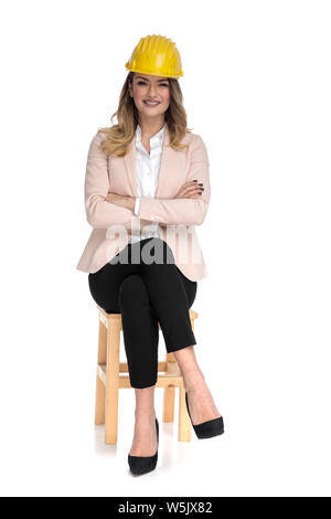 Smart casual young woman wearing cap ingénieur siège sur fond blanc avec bras croisés Banque D'Images