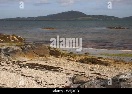 Vue de l'East Kilbride, South Uist, sur la mer d'Eriskay avec une plage rocheuse au premier plan Banque D'Images